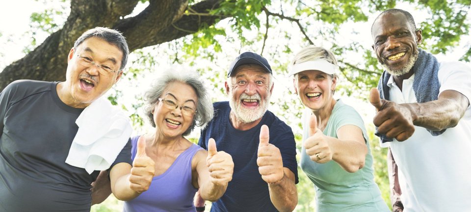 group of senior smiling while raising their thumb finger